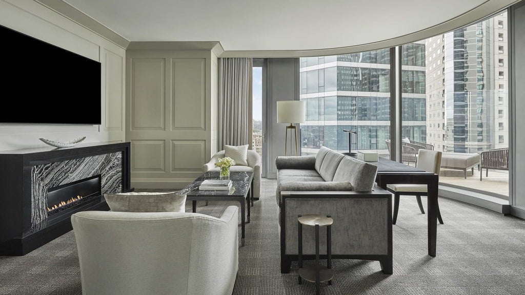 Elegant Charles Suite at Four Seasons One Dalton Street, featuring sophisticated neutral decor, plush king bed, and city skyline view of Boston