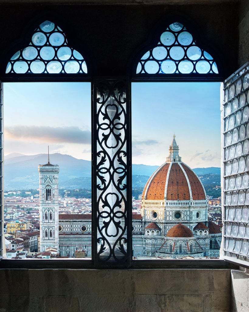 Group of tourists explore charming cobblestone streets of Florence, passing ochre-colored buildings beneath iconic Renaissance architecture