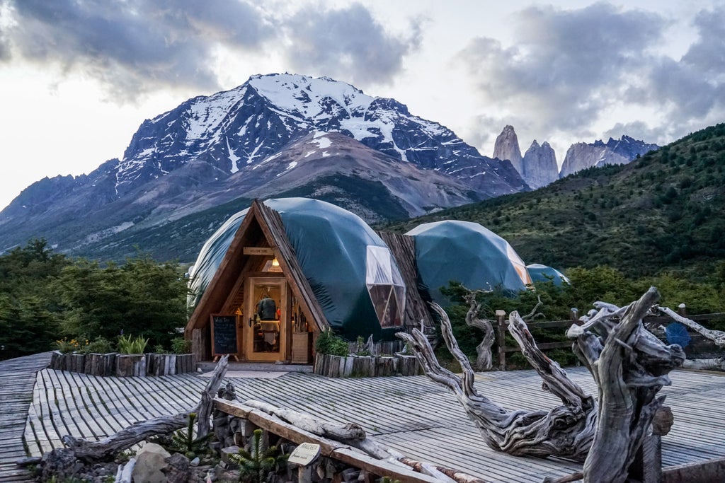 Luxury geodesic dome suites nestled in Torres del Paine National Park, surrounded by snow-capped mountains and lush wilderness