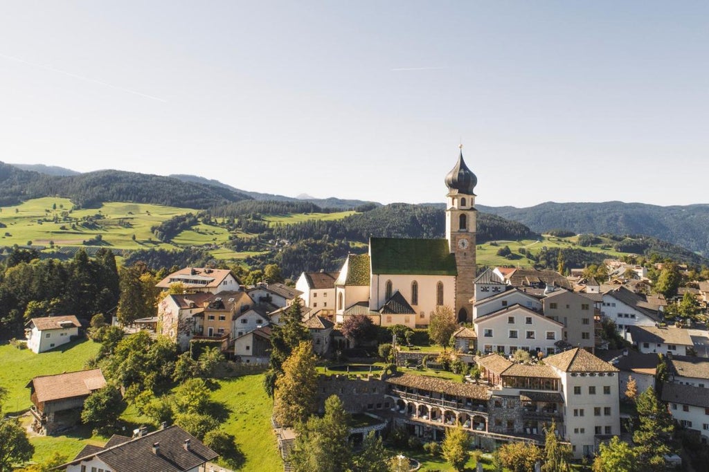 Historic stone tower hotel in South Tyrol with mountain backdrop, featuring traditional architecture and luxury alpine accommodations