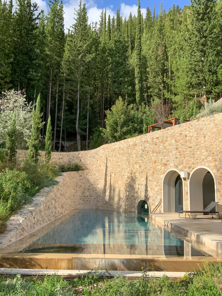 Luxurious infinity pool overlooking lush Greek mountains at sunset, with stone architecture and elegant loungers at Euphoria Retreat