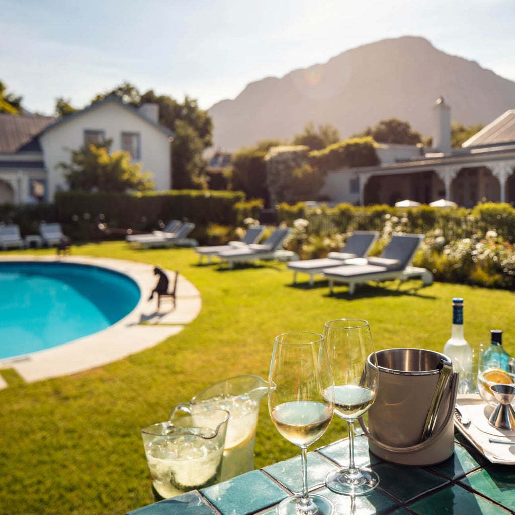 Elegant French colonial-style boutique hotel with white facade, arched windows and manicured gardens in Franschhoek wine country