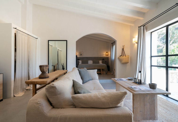 Serene garden suite with private terrace featuring modern decor, white linens, natural wood accents and sweeping views of Mallorca countryside