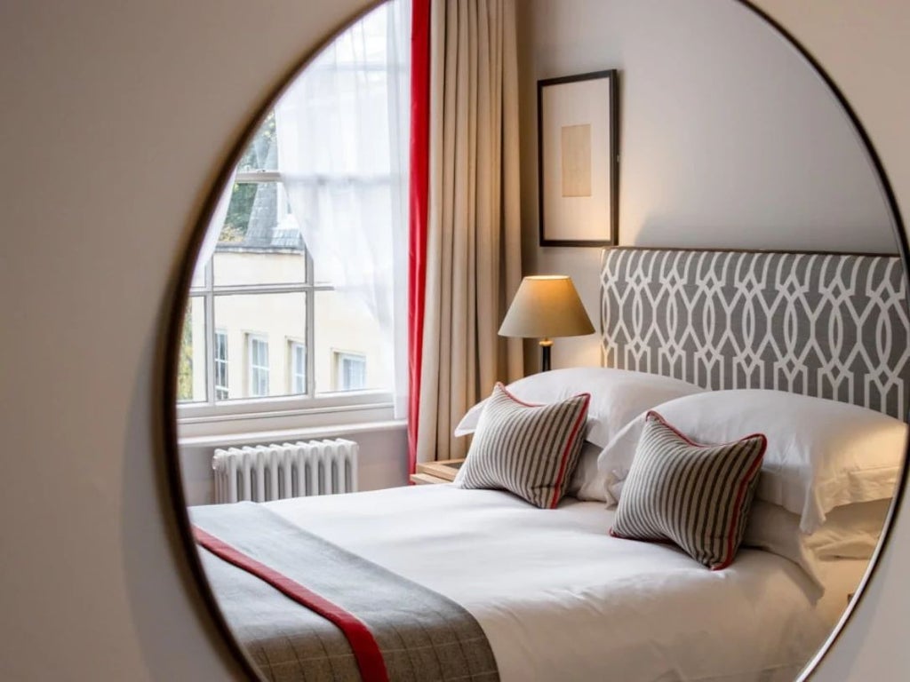 Elegant small double hotel room with classic wooden furnishings, plush white bedding, and refined architectural details from historic bank building.