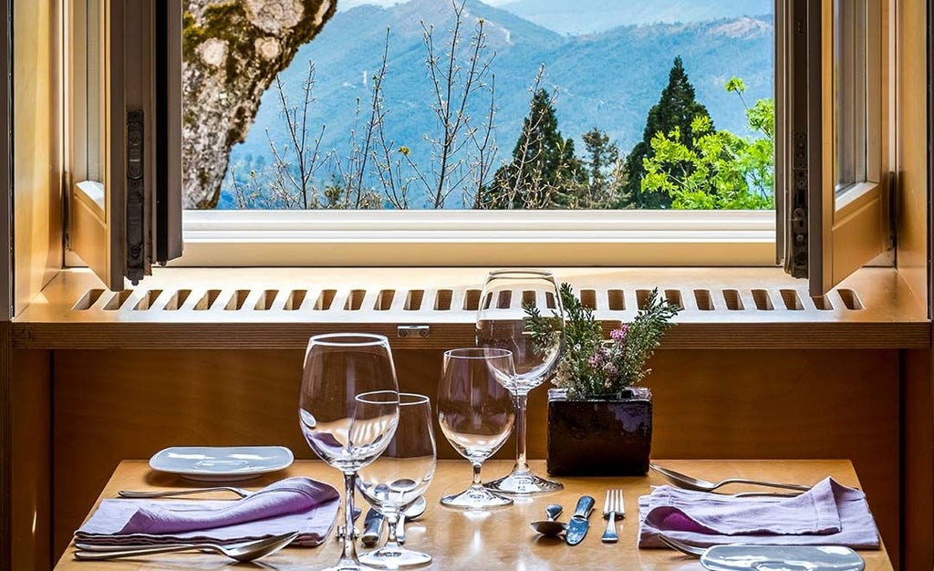 Mountain lodge with minimalist design nestled in Portuguese landscape, featuring clean white architecture, large windows, and panoramic alpine scenery