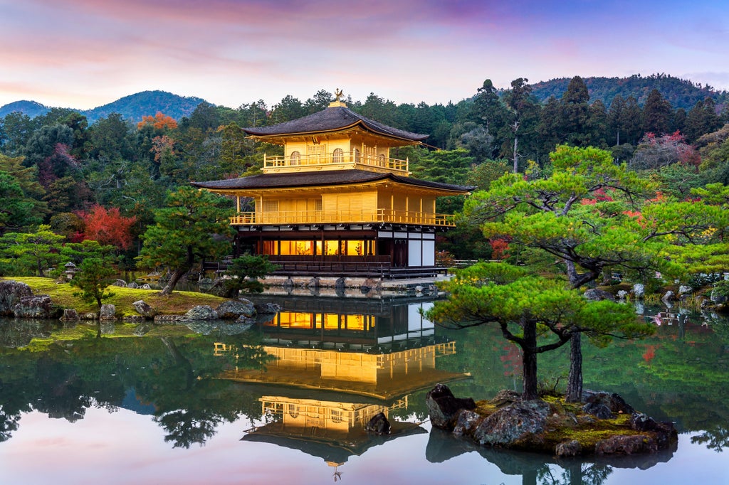 Luxurious golden pavilion reflecting in tranquil pond, surrounded by meticulously landscaped Japanese gardens with maple trees in Kyoto's cultural landscape