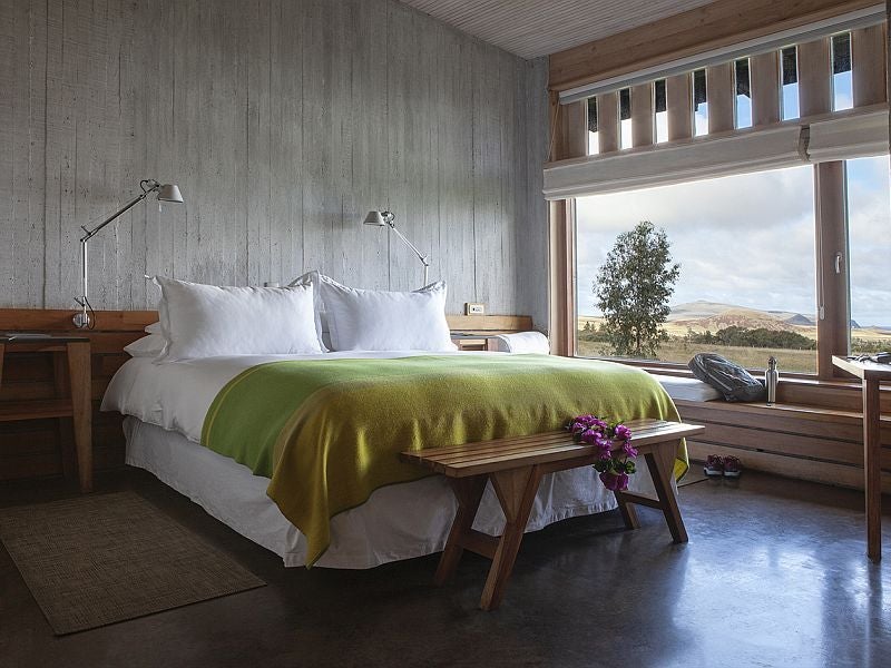 Minimalist luxury room with panoramic ocean view, wooden decor, and modern Chilean design at Explora Rapa Nui Lodge's Varua Room on Easter Island