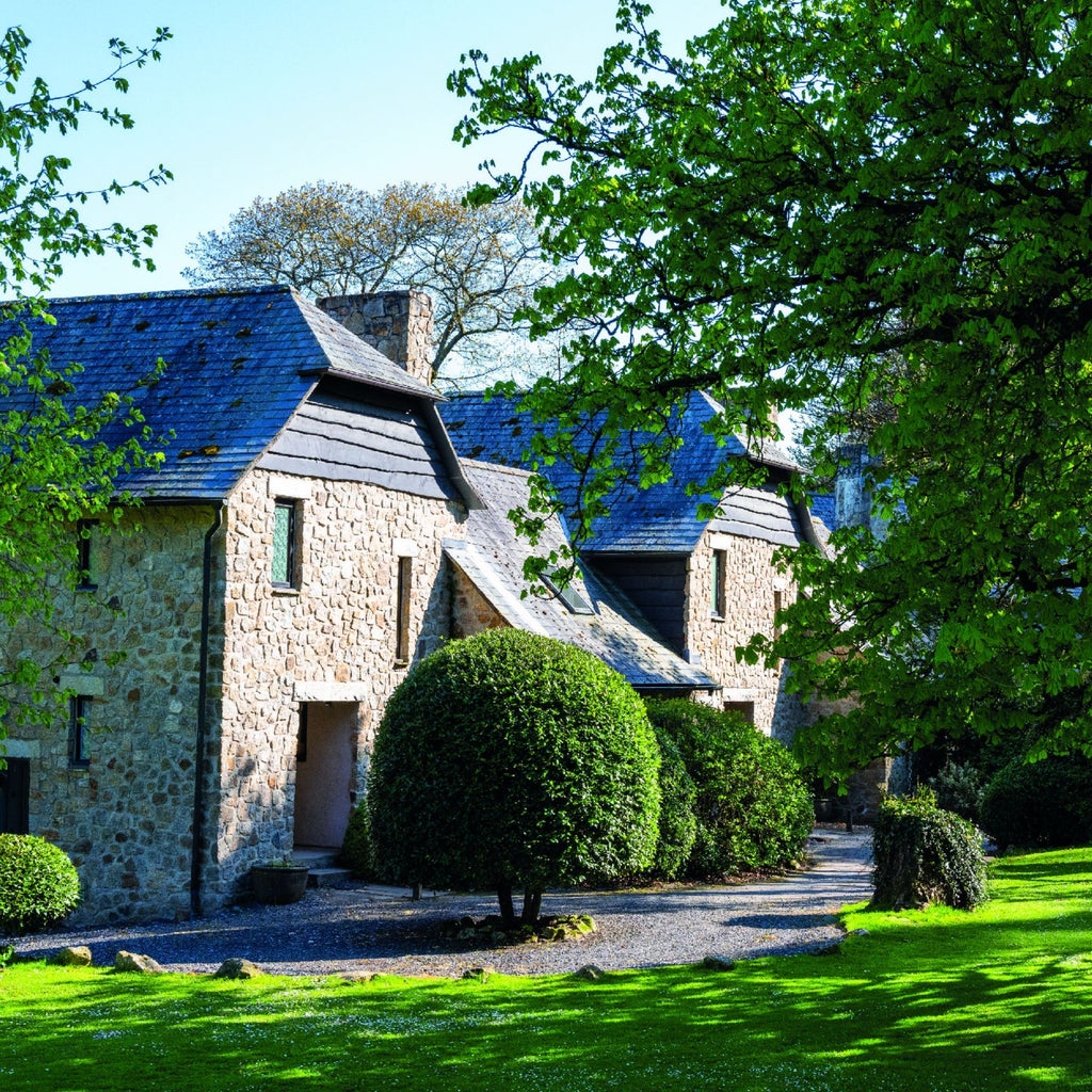 Luxurious stone manor hotel nestled in lush Devon countryside, featuring elegant architecture, manicured gardens, and expansive green landscape