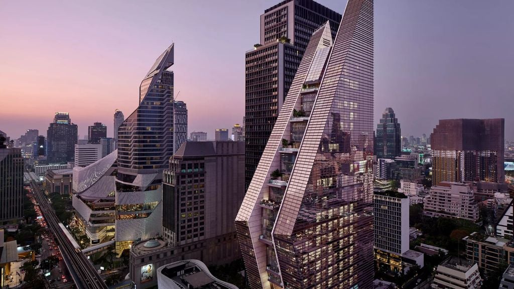 Modern triangular glass skyscraper hotel with architectural twists, rising dramatically against Bangkok skyline at sunset, reflecting golden light