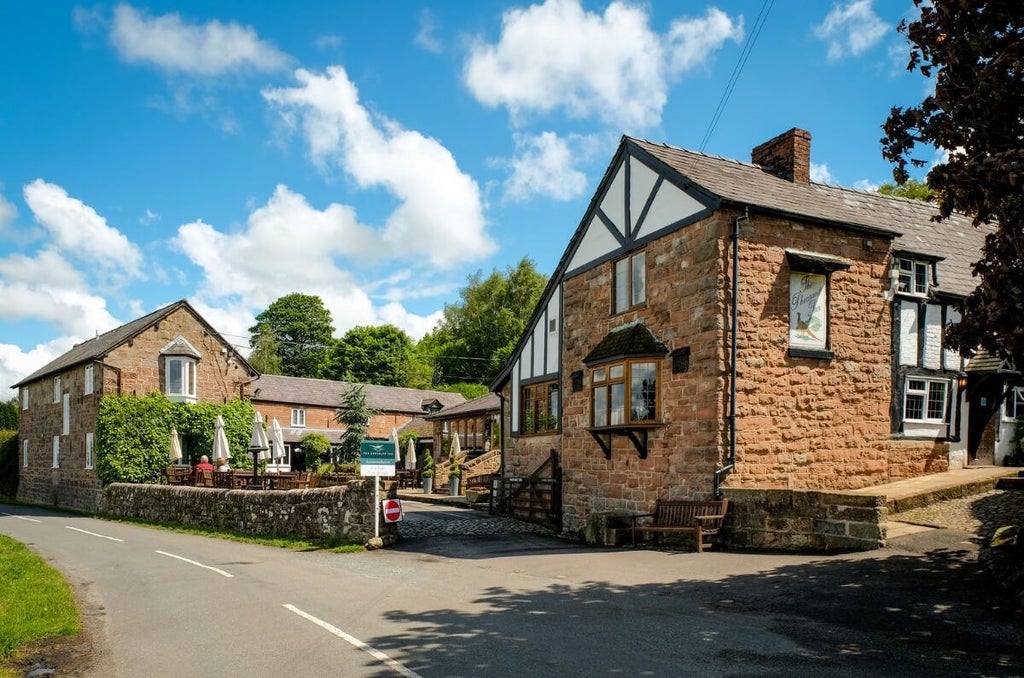 Elegant countryside hotel with stone facade, traditional British architecture, warm lighting, and lush green landscape at dusk near scenic rural setting