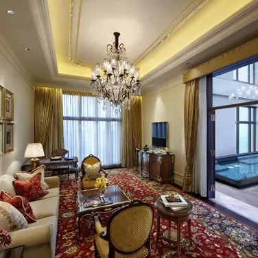 Opulent royal parlour suite at luxury hotel, featuring elegant gold-trimmed furniture, expansive marble floors, and panoramic city views of New Delhi landscape