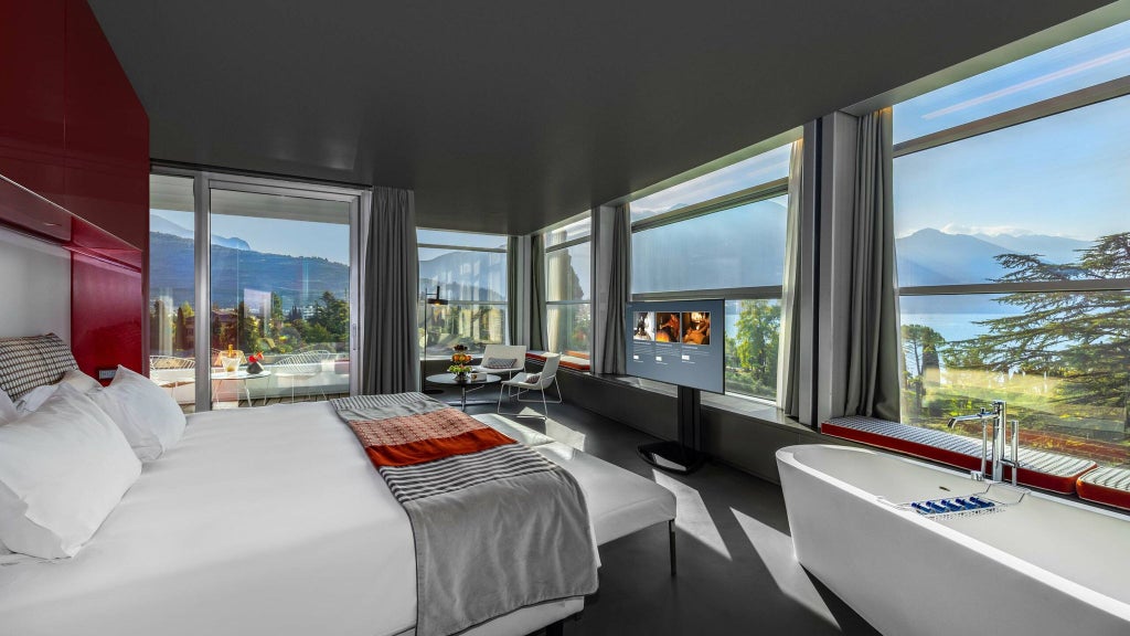 Elegant sky-view suite at Lido Palace with contemporary Italian design, expansive windows, plush king bed, and panoramic Alps mountain landscape backdrop