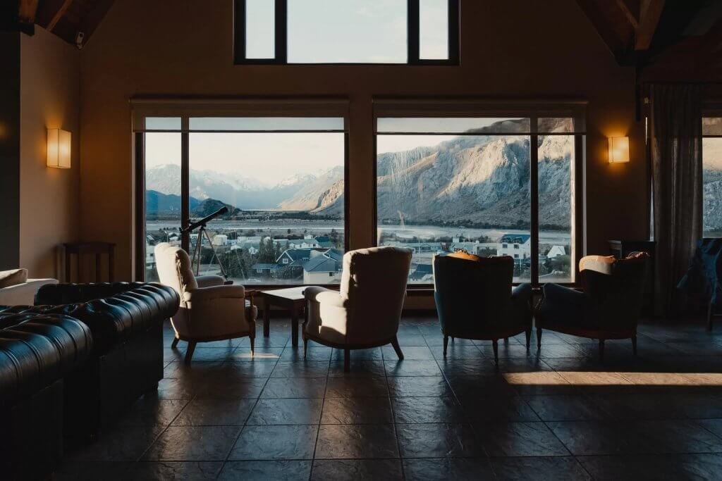 Luxurious boutique hotel nestled in scenic Argentine mountains, featuring modern architecture with warm wood tones and expansive glass windows overlooking lush landscape