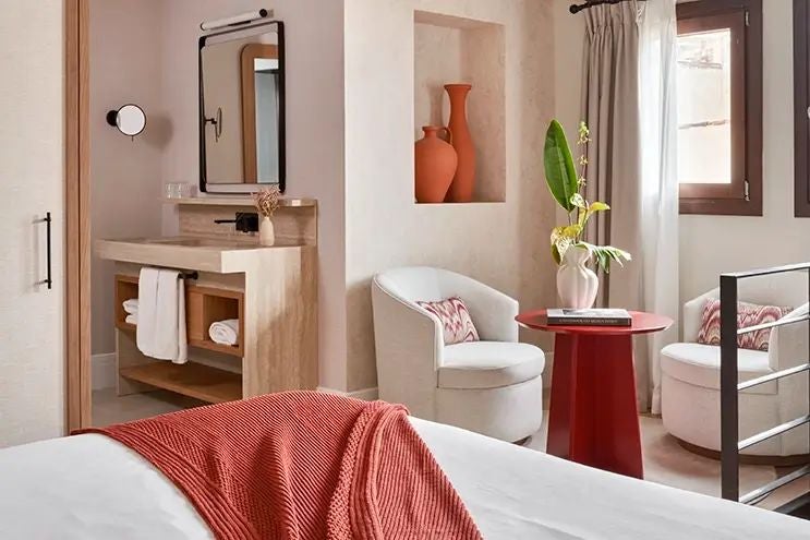 Luxurious duplex hotel room at Scenset Terra Santa, featuring elegant wooden furnishings, rustic stone walls, and plush bedding in a warm, inviting Spanish aesthetic