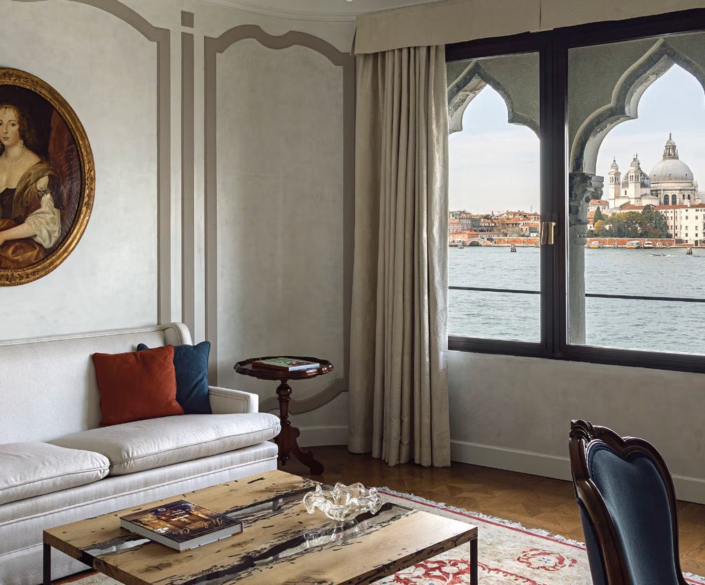 Opulent hotel suite with panoramic St. Mark's views through floor-to-ceiling windows, featuring elegant Italian furnishings and marble accents