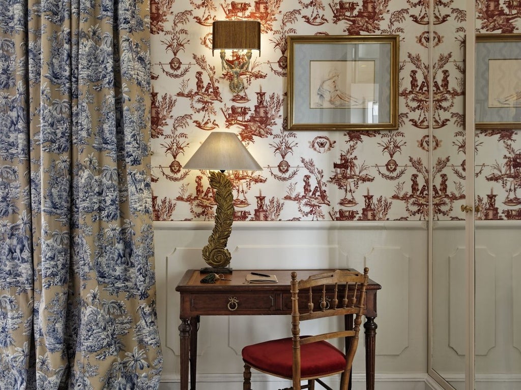 Elegant 17th century Parisian boutique hotel with ivy-covered walls, wrought iron gates and classic French windows lit by warm lanterns