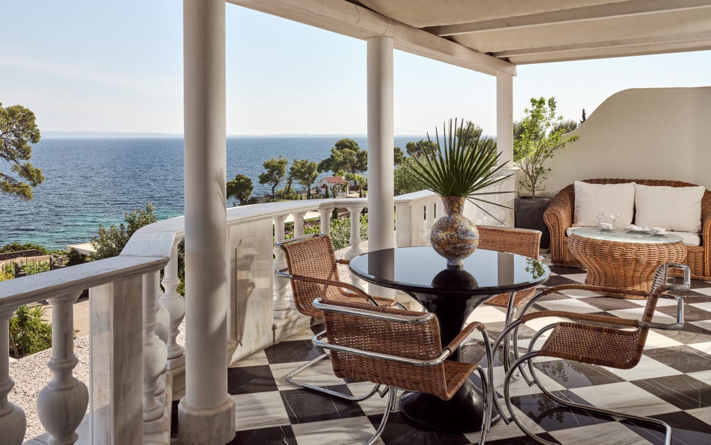 Luxurious Mediterranean Suite with panoramic Aegean Sea view, elegant white interiors, private balcony, and minimalist design showcasing coastal Greece's serene ambiance