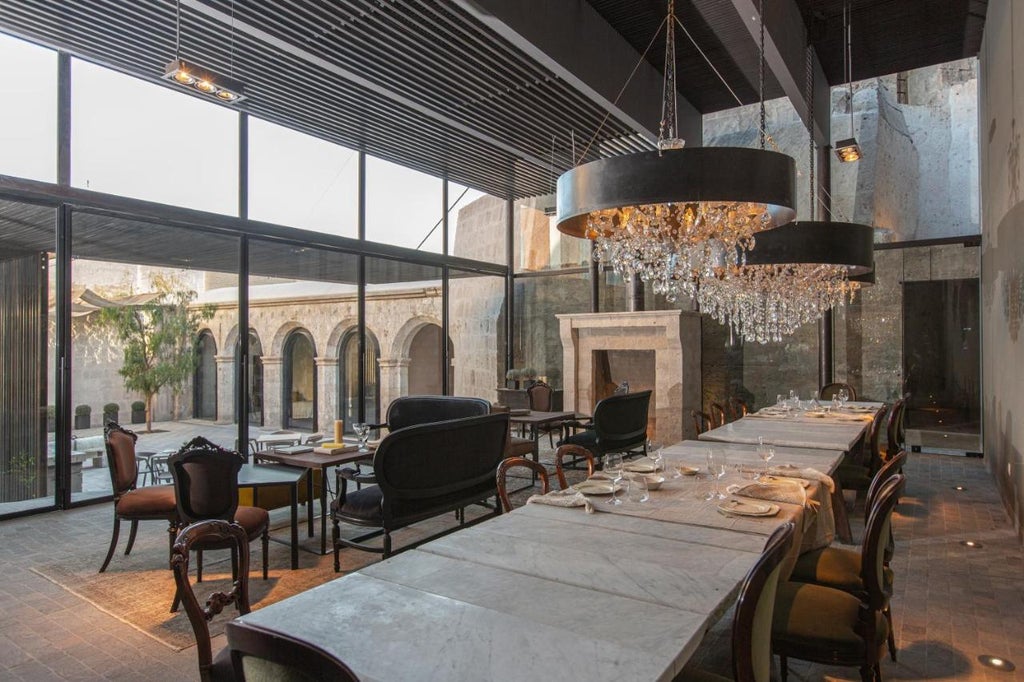 Sunlit colonial courtyard of Cirqa hotel with white stone archways, potted palms, and rustic wooden furniture creating an elegant atmosphere