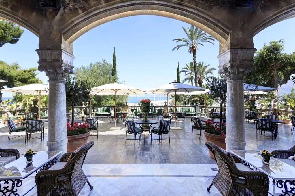 Elegant Mediterranean hotel Villa Igiea with grand stone facade, ornate balconies, and lush gardens overlooking the Sicilian coastline