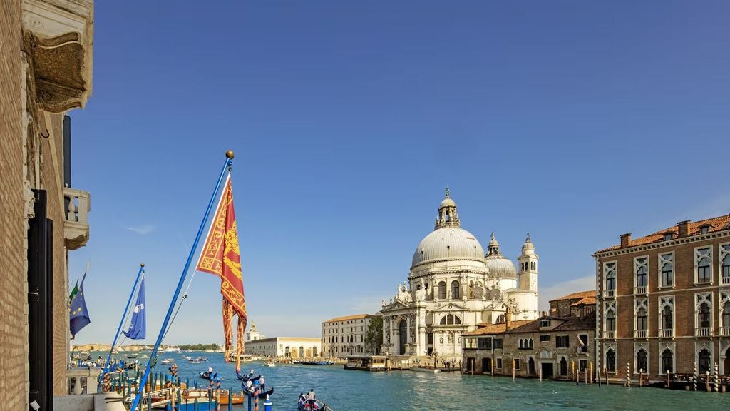 Opulent Venetian suite with crystal chandeliers, ornate gold-framed mirrors, antique furniture, and panoramic Grand Canal views from tall windows