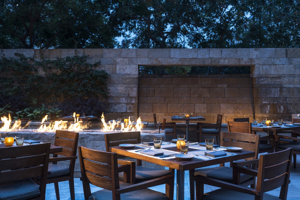 Modern luxury hotel exterior with glass facade, palm trees and white columns at sunset, Four Seasons Silicon Valley in Palo Alto