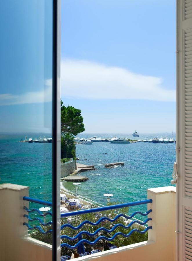 Elegant art deco Hotel Belles Rives on French Riviera with blue-white striped beach chairs, seaside terrace, and Mediterranean views