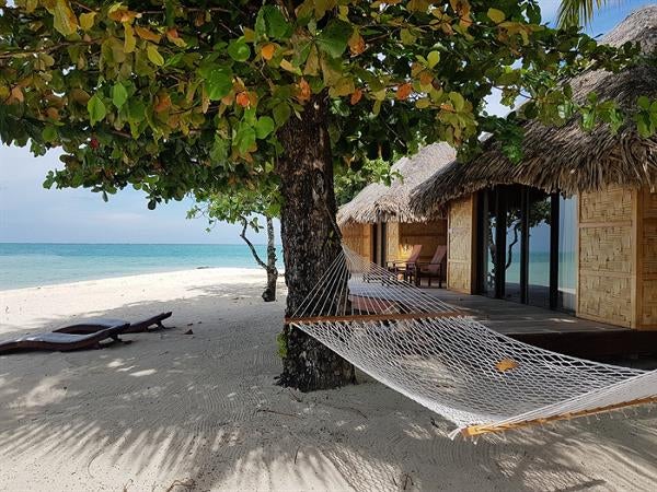 Luxurious overwater villa with private pool overlooking turquoise lagoon, featuring thatched roof and wooden deck with loungers