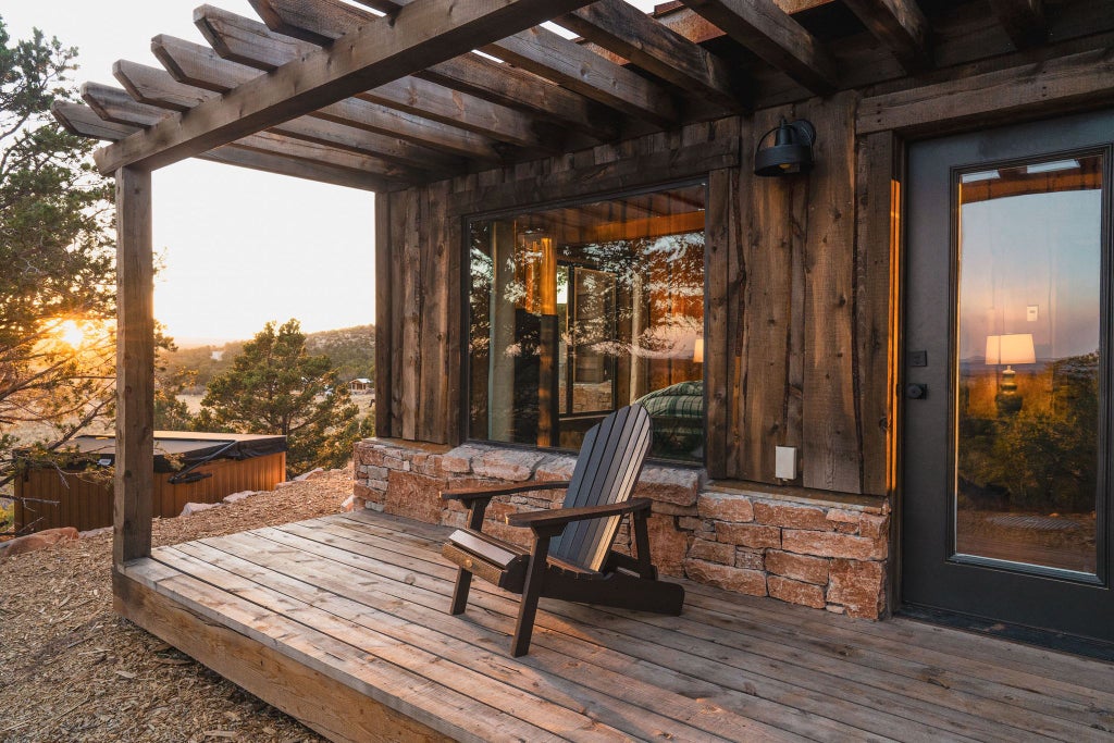 Rustic lodge room with wooden furnishings, plush bedding, and panoramic window overlooking scenic mountain landscape at Scenset Mountain Ranch