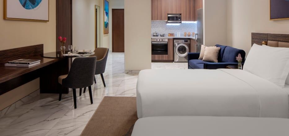 Spacious modern studio suite with panoramic city skyline view, featuring sleek contemporary furnishings and floor-to-ceiling windows in Dubai's Scenset Hotel