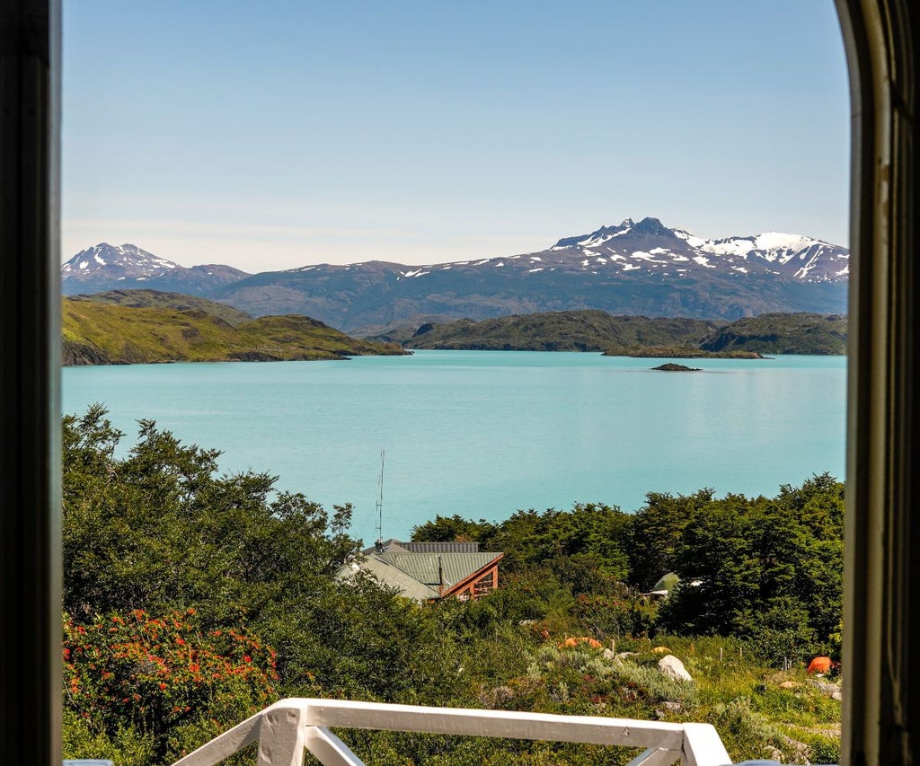 Rustic wooden mountain cabin interior with panoramic windows overlooking dramatic Patagonian peaks at Hotel Las Torres Patagonia, Chile