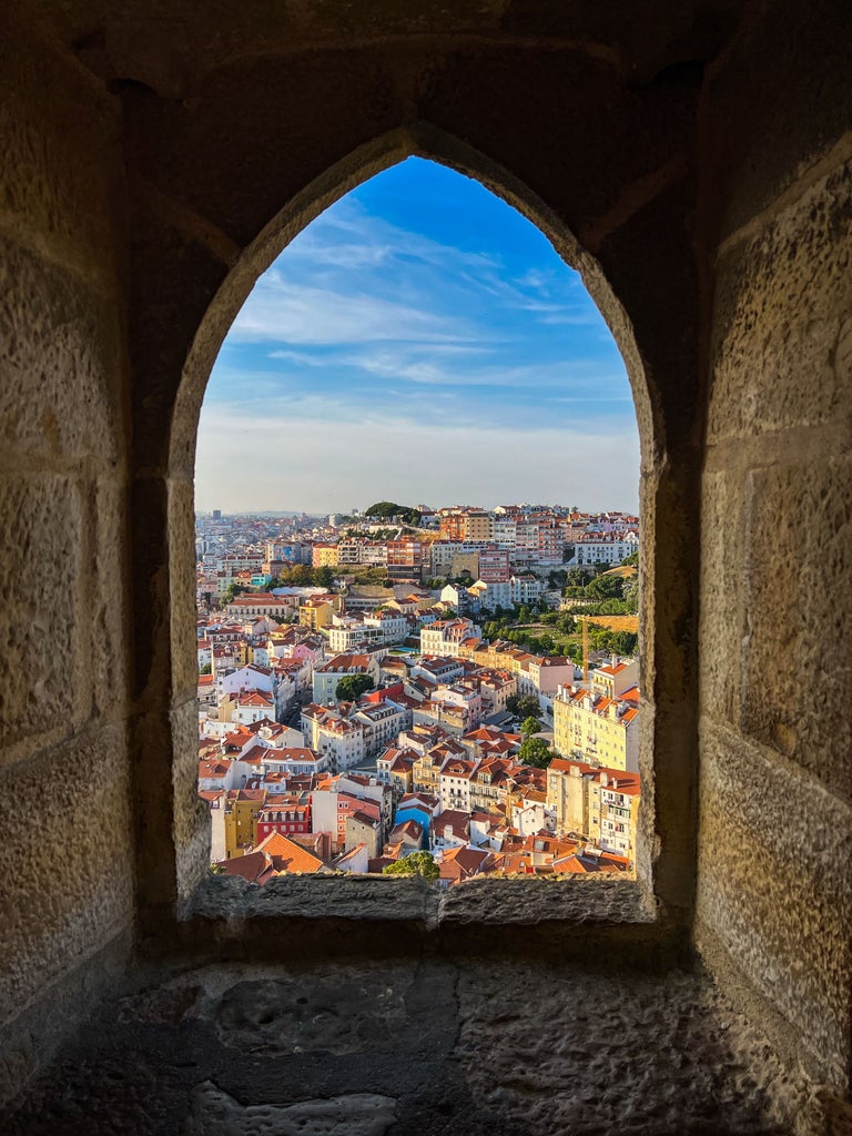 Colorful vintage tuk tuk touring scenic Portuguese cobblestone streets, with vibrant buildings and lush landscape in golden afternoon sunlight