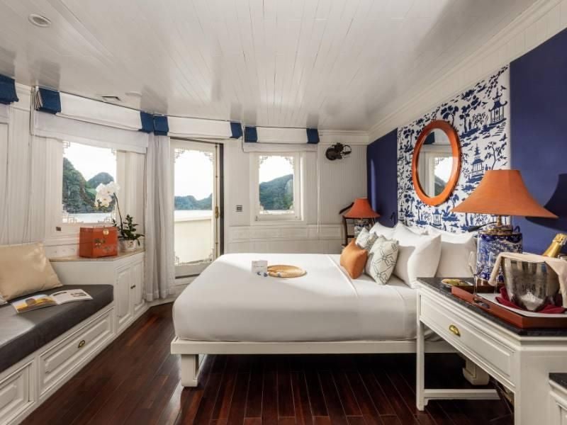 Luxurious Au Co Suite aboard Bhaya Cruises, featuring elegant Vietnamese-inspired decor, expansive windows overlooking emerald Halong Bay waters