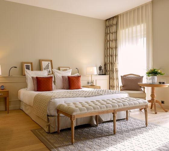 Elegant deluxe hotel room with plush white bedding, soft gray textured walls, and sophisticated French contemporary design in Cognac, France