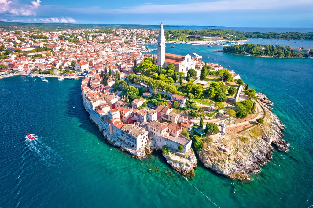 Elegant Roman amphitheater dominates Pula's skyline as crystal-blue Adriatic waters meet historic Rovinj's colorful waterfront buildings