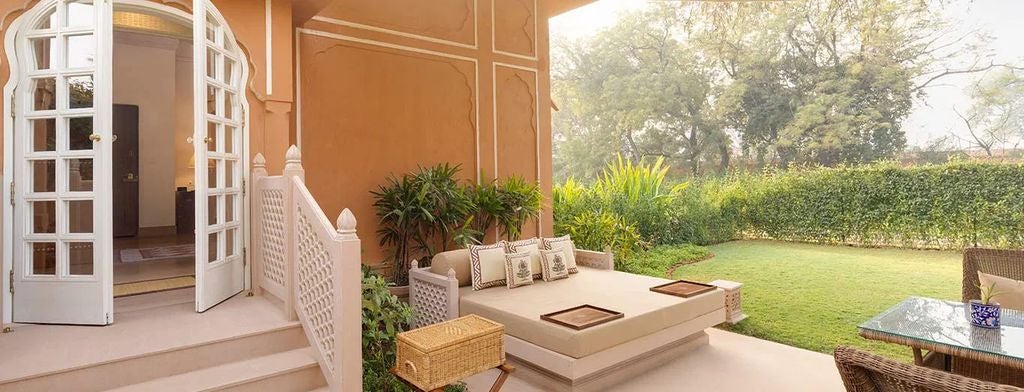 Elegant sandstone archways and domes of Oberoi Rajvilas hotel with manicured gardens, reflecting traditional Rajasthani palace architecture