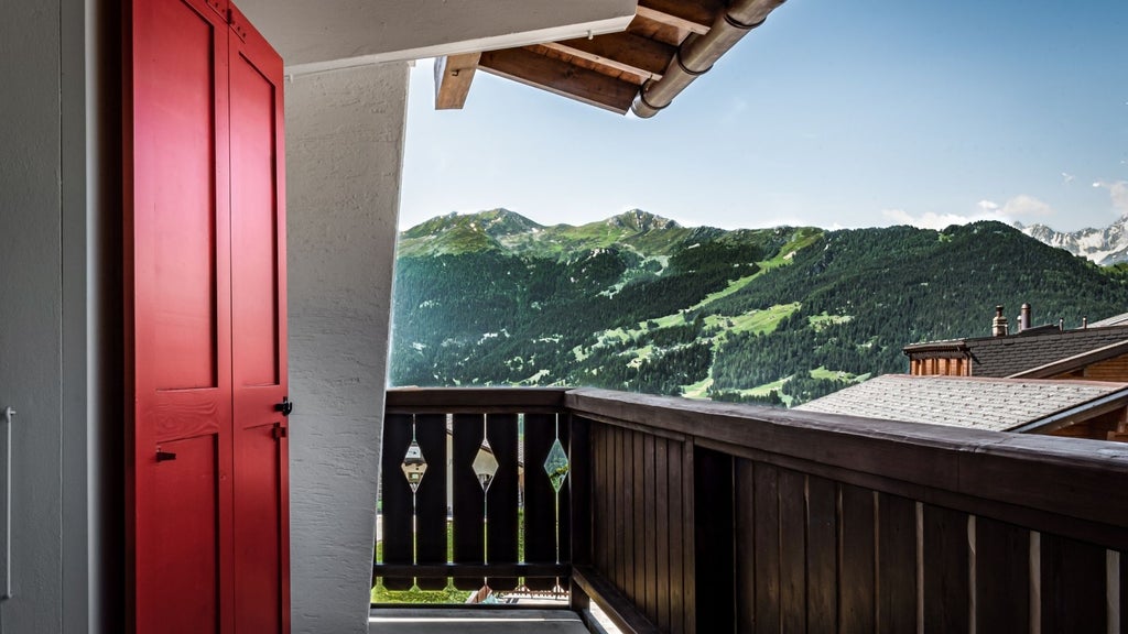 Luxurious Panorama Suite with floor-to-ceiling windows, alpine wood paneling, modern minimalist furnishings, and breathtaking Swiss mountain landscape view