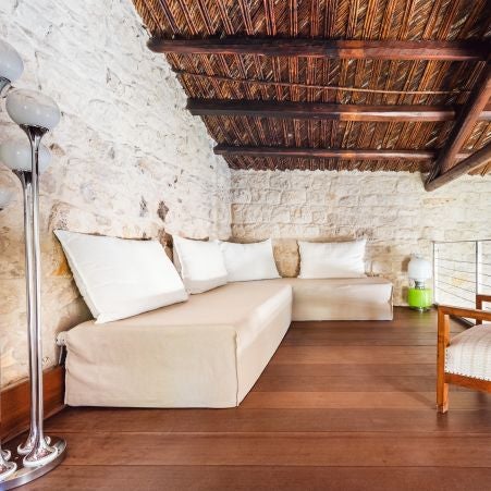 Elegant rustic-chic hotel room with exposed stone walls, minimalist wooden furniture, and soft natural light in a historic Italian setting