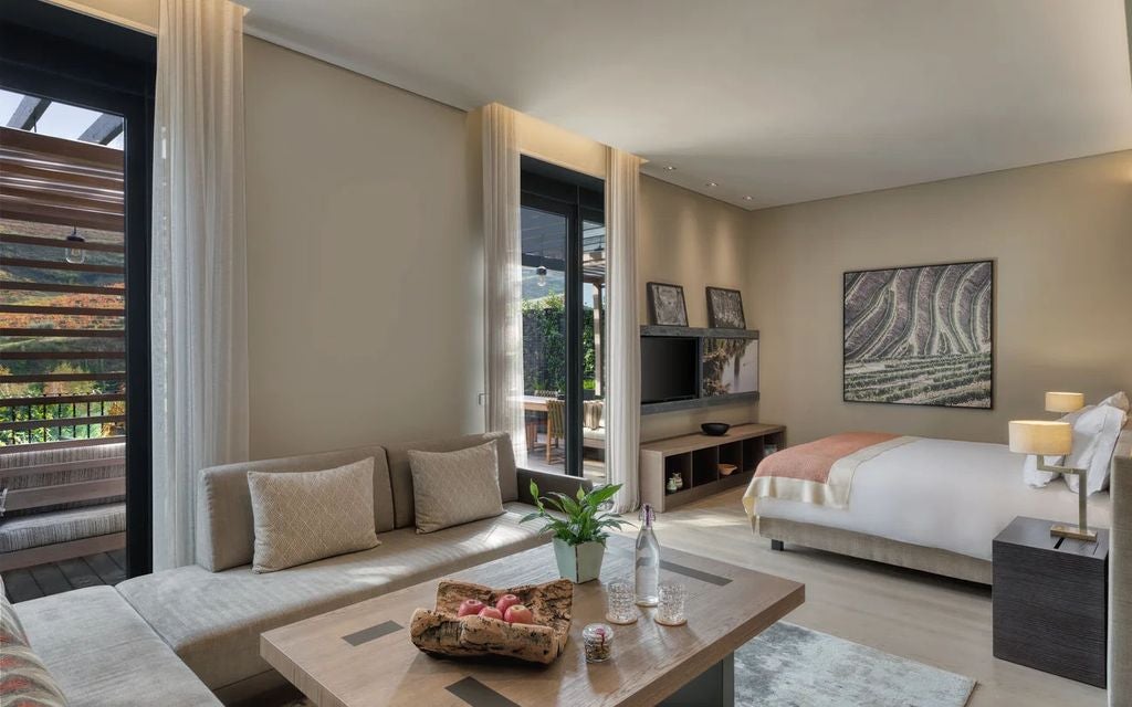 Luxurious hotel room with floor-to-ceiling windows overlooking Douro Valley vineyards, featuring modern decor and warm wood accents