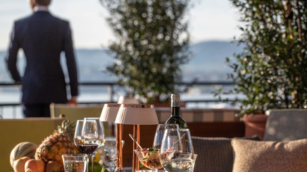 Luxurious waterfront hotel with elegant Swiss architecture overlooking Lake Zurich, featuring pristine blue waters and alpine mountain backdrop