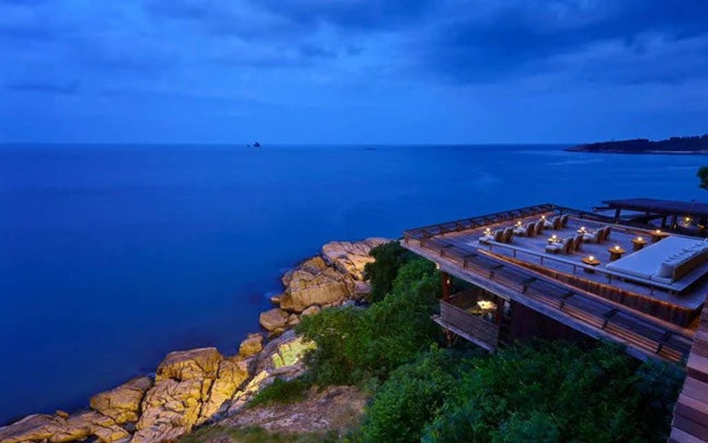 Luxurious infinity pool overlooking turquoise ocean at Six Senses Samui resort, with wooden deck and tropical landscaping