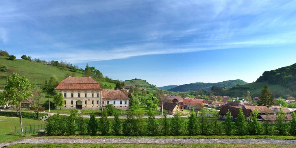 Luxurious renovated historic stone manor nestled in Transylvanian countryside, featuring rustic elegance with modern architectural details and lush green landscape