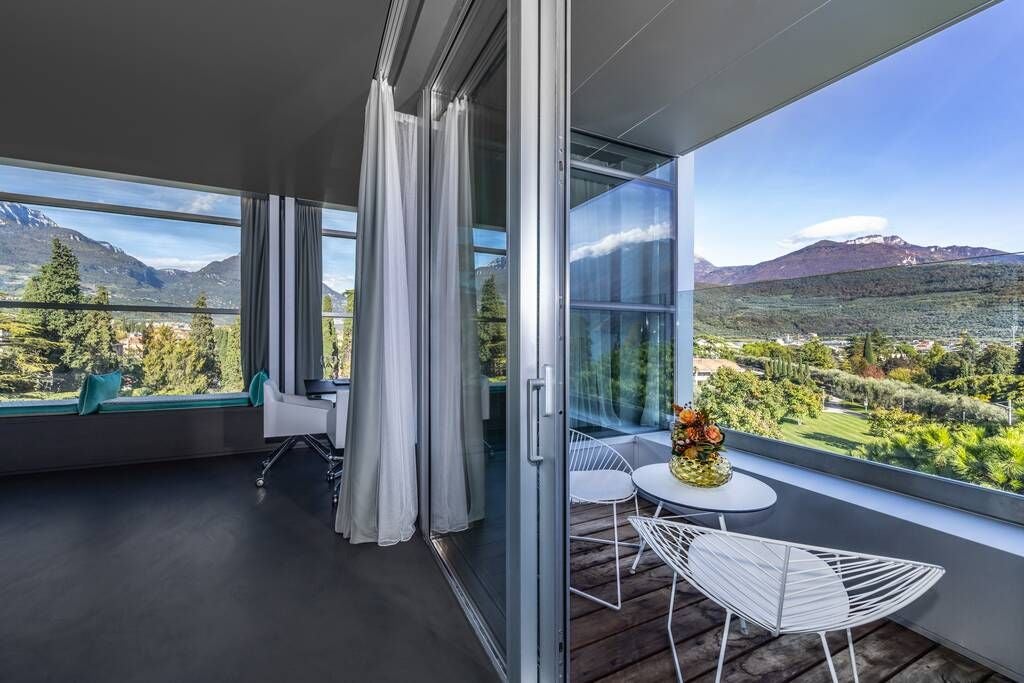 Opulent sky mountain suite with panoramic alpine views, modern minimalist design, plush king bed, and floor-to-ceiling windows overlooking Italian landscape