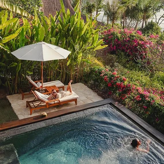 Luxurious open-air Kanatar Villa at NIHI Sumba, featuring panoramic ocean views, elegant wooden decor, and a private infinity pool nestled in lush Indonesian landscape