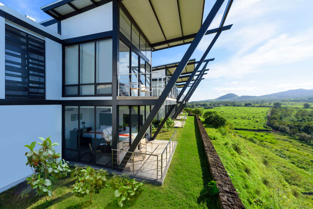 Luxurious eco-lodge perched on volcanic terrain, overlooking lush Galapagos landscapes with modern architecture blending seamlessly into pristine natural environment.