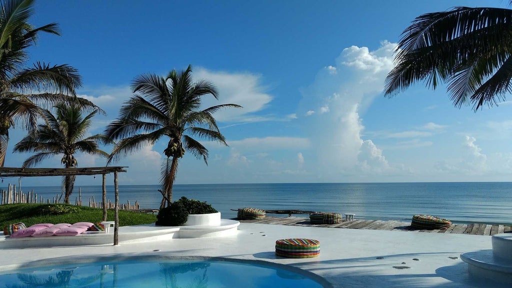 Luxurious white beachfront hotel with elegant architecture, overlooking turquoise waters and pristine sandy coastline in coastal Mexican destination