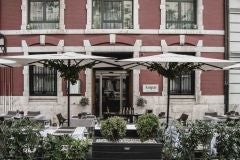 Elegant white-washed luxury hotel exterior in Valencia, featuring neoclassical architecture with lush palm trees and refined Mediterranean design aesthetic