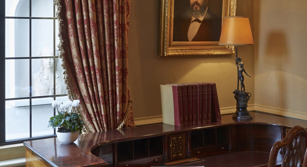 Opulent boutique hotel room with ornate vintage furnishings, plush velvet armchair, and elegant canopy bed in a historic London setting