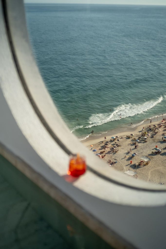 Sleek modern hotel room with panoramic ocean view, minimalist design, floor-to-ceiling windows, elegant wooden furnishings in Janeiro Hotel, Brazil