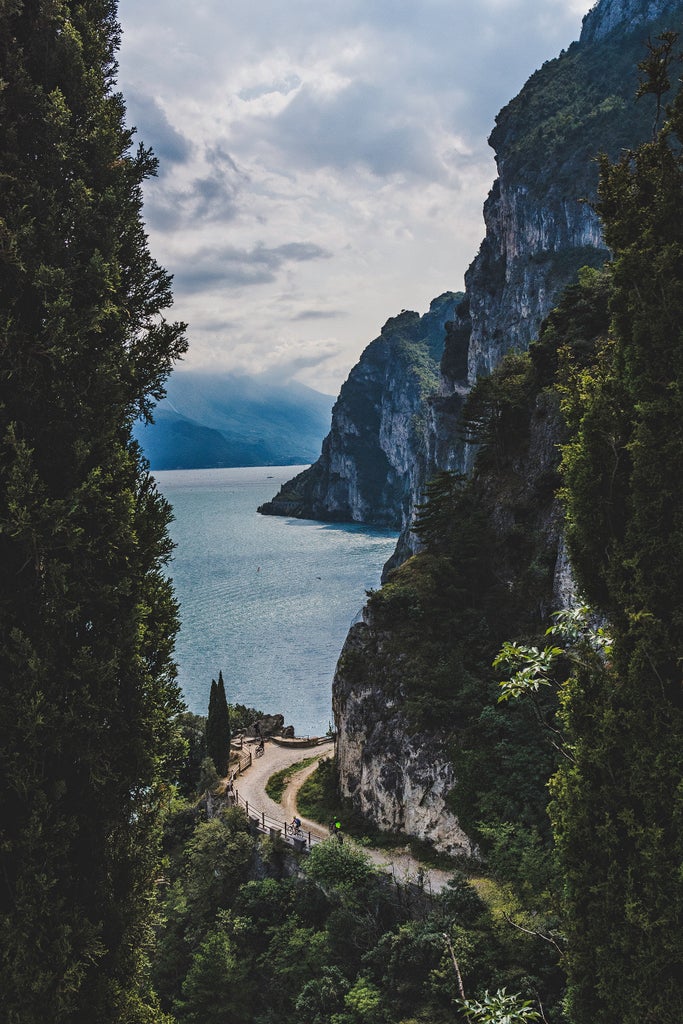 Scenic Lake Garda shoreline with luxury boats docked at wooden piers, crystal-clear turquoise waters surrounded by dramatic mountains