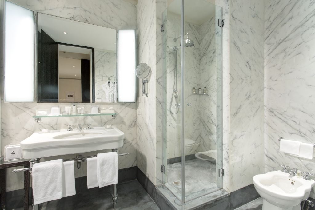 Luxurious studio deluxe hotel room in Roma, featuring elegant marble bathroom, plush king bed, and refined contemporary Italian design with warm neutral tones